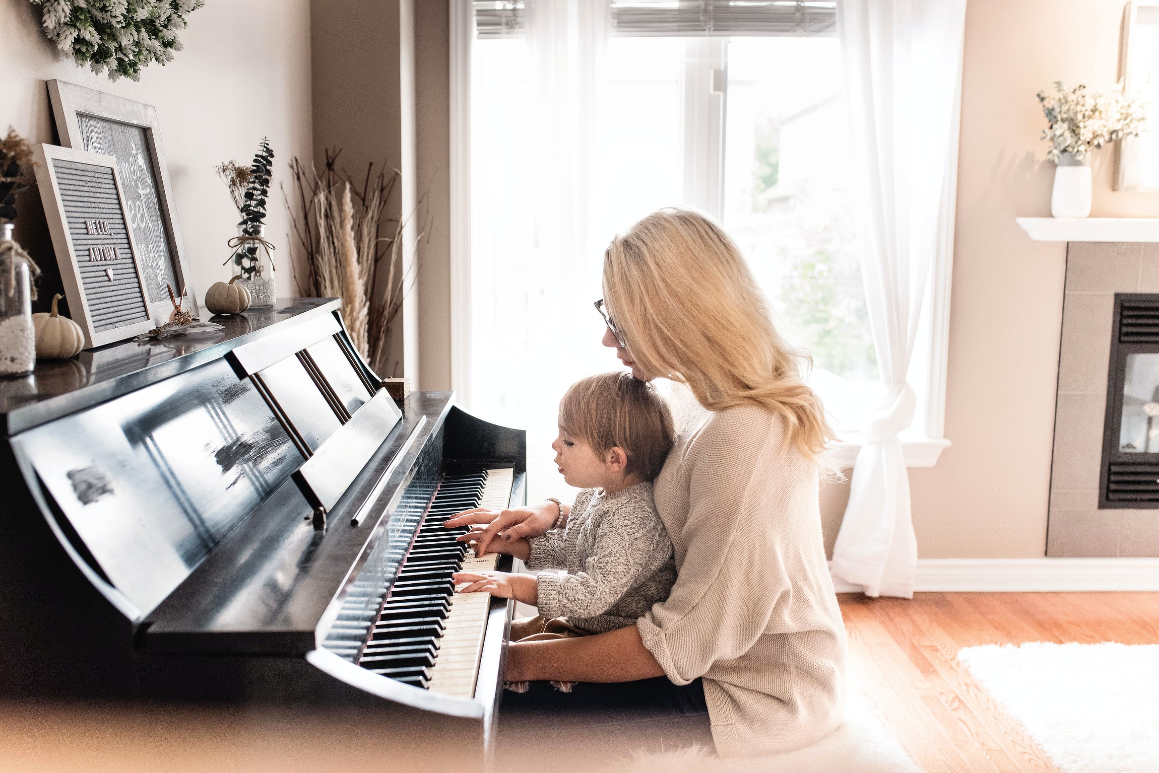 Foto de una mujer tocando el piano con un niño pequeño